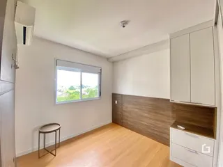 Quarto com piso de madeira clara e janela iluminada.