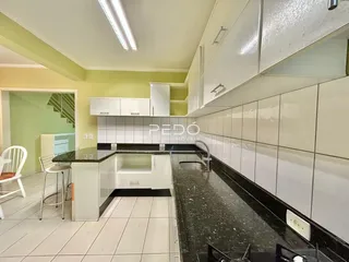 Foto de uma cozinha com armários brancos e bancadas escuras em um imóvel no Brasil.