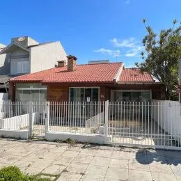 Fachada de uma residência com telhado de telhas vermelhas e cerca branca.