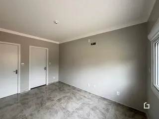 Interior de um corredor com piso de cerâmica e paredes cinzas.