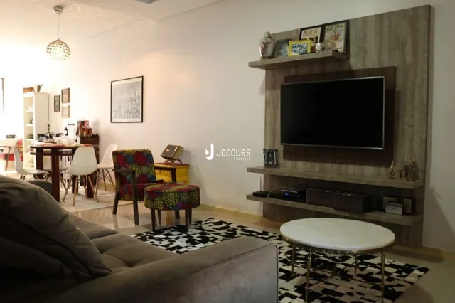 Sala de estar com sofá e televisão montada na parede em um imóvel.