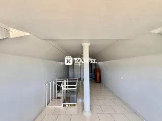 Corredor interno de um imóvel com piso de cerâmica e coluna central.