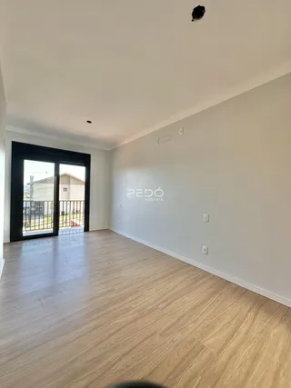 Ambiente interno com piso de madeira clara e porta de vidro abrindo para o exterior.
