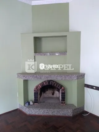 Uma lareira embutida com revestimento de pedra e tijolos está instalada na parede da sala.
