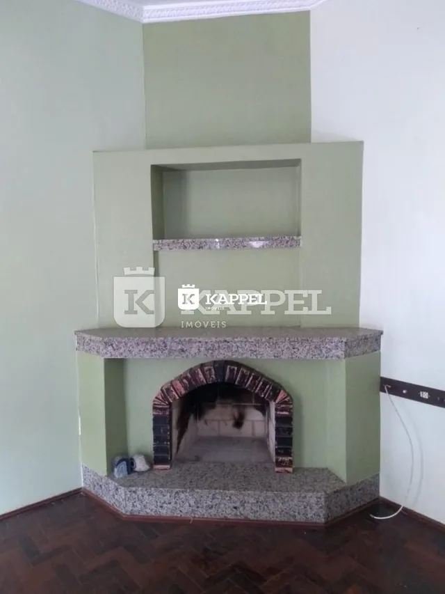 Uma lareira embutida com revestimento de pedra e tijolos está instalada na parede da sala.