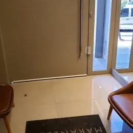Vista interna de um ambiente com piso claro e porta de vidro.