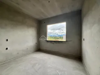 Sala ampla com piso de cerâmica e uma grande janela que oferece uma vista da paisagem externa.