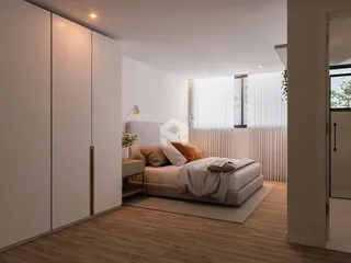 Quarto moderno com piso de madeira clara e grandes janelas.