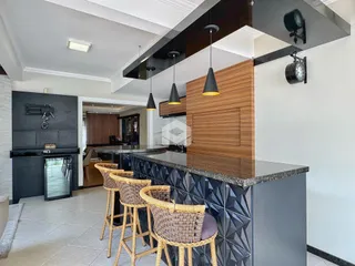 Ambiente de cozinha moderna com ilha central e bancos de madeira.