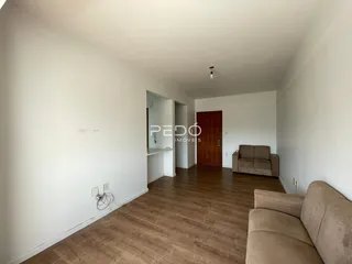 Ambiente interno de uma sala com piso de madeira clara.