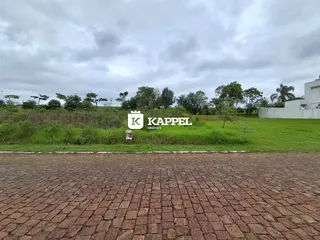 Vista externa do terreno com grama e vegetação ao fundo.
