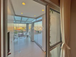 Sala de estar com vista para o exterior através de grandes portas de vidro.
