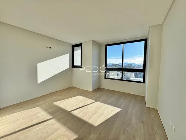 Ambiente interno de uma sala com piso de madeira clara e grande janela.
