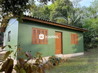 Fachada externa de uma casa verde com venezianas de madeira.