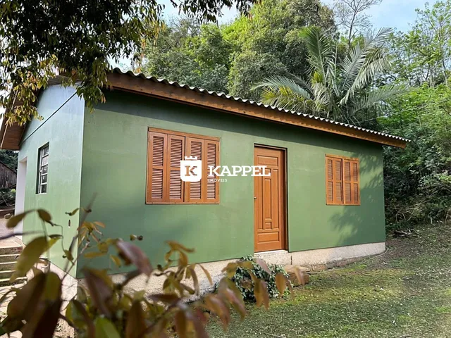 Fachada externa de uma casa verde com venezianas de madeira.