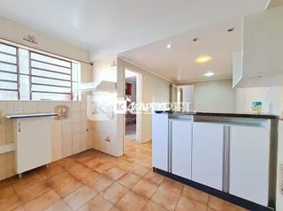 Foto interna de uma cozinha com piso de cerâmica e armários brancos.