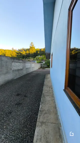 Vista externa da propriedade mostrando um muro e uma área pavimentada.