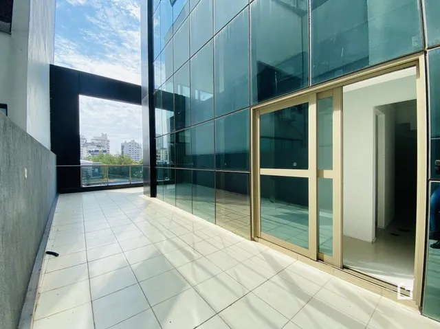 Vista de um corredor interno com piso de cerâmica e paredes de vidro.