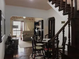 Sala de estar com piso de madeira e escadaria em uma residência.