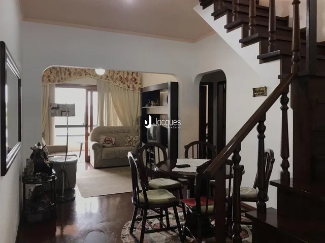 Sala de estar com piso de madeira e escadaria em uma residência.