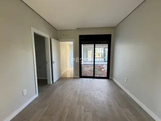 Corredor interno de uma residência com piso de madeira clara e portas brancas.