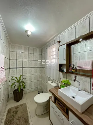 Foto de um banheiro com revestimento de cerâmica branca e louças sanitárias.