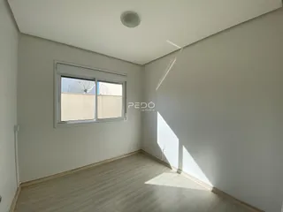 Vista interna de um cômodo com piso de madeira clara e paredes brancas.