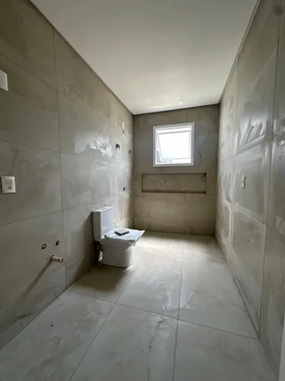 Banheiro com piso de cerâmica claro e paredes neutras.