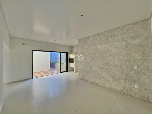 Ambiente interno moderno com piso claro e porta de vidro que se abre para o exterior.