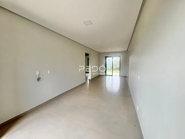 Hall de entrada longo com paredes brancas e piso claro.