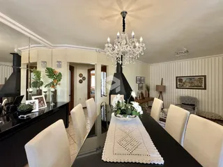 Uma sala de jantar com mesa escura e cadeiras brancas.