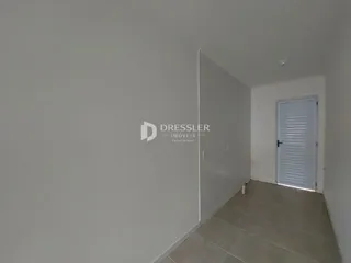 Hall de entrada com paredes brancas e piso claro.