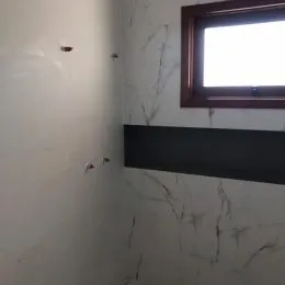 Detalhe de uma parede branca com uma faixa escura horizontal em um imóvel.