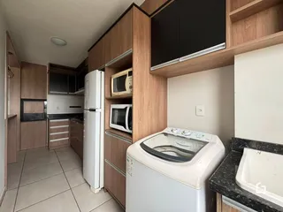 Cozinha com armários de madeira e eletrodomésticos brancos em um imóvel no Brasil.