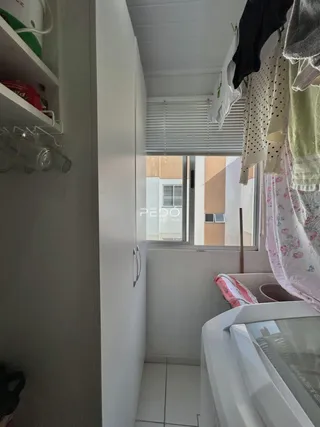 Vista interna de um corredor com armário branco e janela em um imóvel no Brasil.