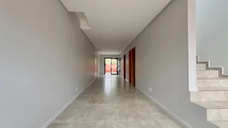 Corredor interno de uma residência com piso de cerâmica clara.