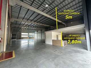 Imagem de um espaço interno com piso de concreto e estrutura de telhado metálico.