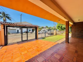 Vista da fachada da propriedade com piso de tijolos e portão de ferro.