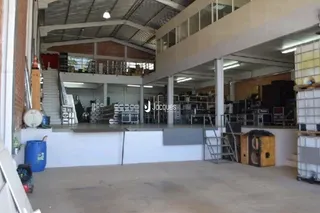 Espaço interno com estrutura de teto exposta e piso de concreto.
