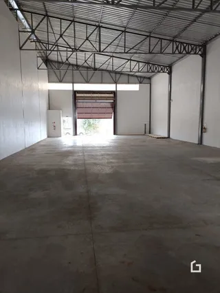 Foto de um espaço interno com piso de concreto e estrutura metálica exposta.