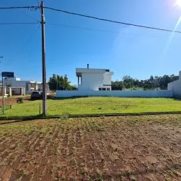 Vista externa de um terreno com gramado aberto sob céu azul.