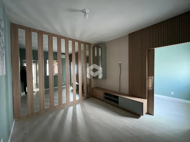 Interior de uma sala com painéis de madeira e piso claro.