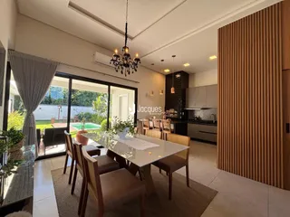 Sala de estar e jantar moderna com portas de vidro que dão acesso a um jardim.