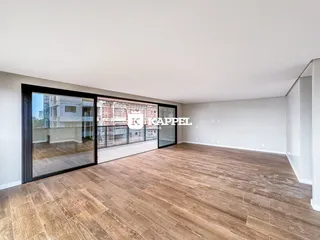 Sala de estar com piso de madeira e portas de vidro que dão acesso ao exterior.