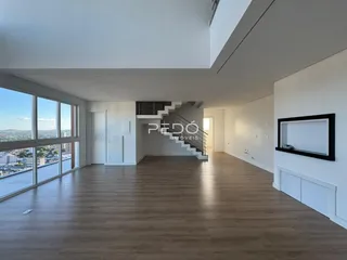 Interior de um apartamento moderno com piso de madeira e grande janela com vista para a cidade.