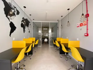 Uma sala de jantar longa com mesas e cadeiras amarelas em um imóvel no Brasil.