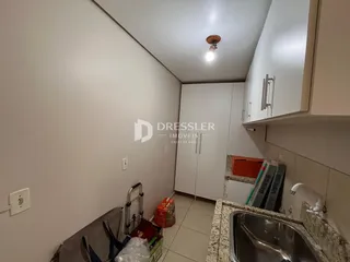 Vista interna de uma cozinha com armários brancos e pia.