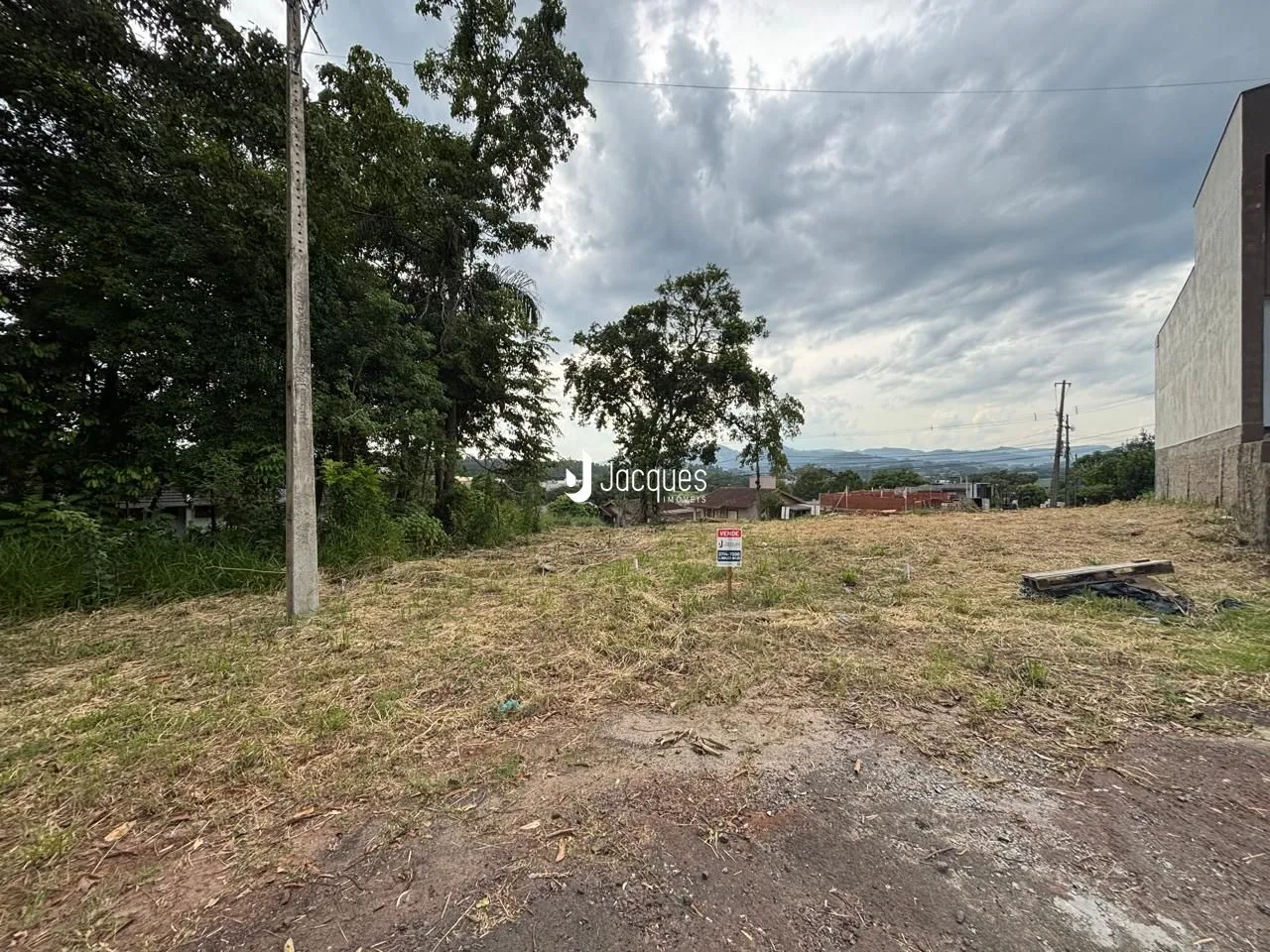 Vista de um terreno aberto com vegetação e campo seco.