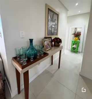 Hall de entrada com um aparador de madeira e quadros.