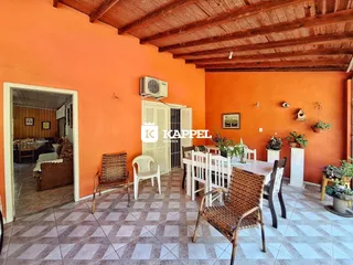Sala de jantar com mesa e cadeiras de vime em um ambiente com paredes laranjas.